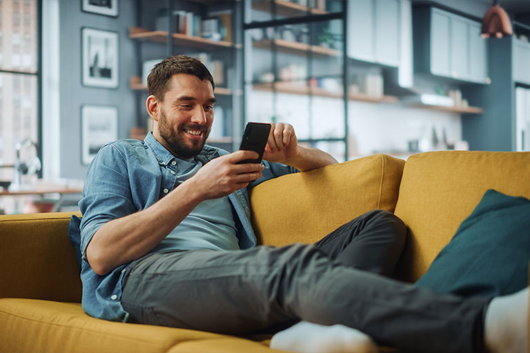 Man relaxed on couch looking at cell phone